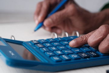 senior women use calculator and writing on notepad 
