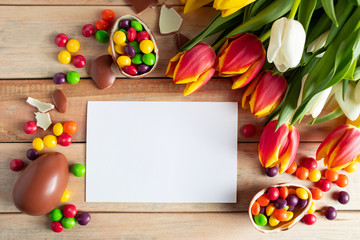 Easter composition of chocolate eggs and tulips. Empty greeting card for festive design.