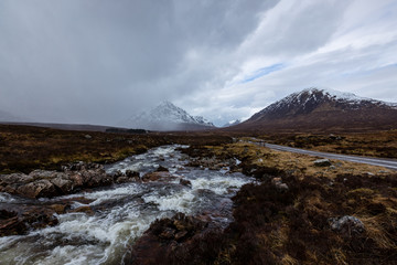 Fototapeta na wymiar the river coupall waterfalls on rannoch moor showing buachaille etive mor in the background as the entrance to glencoe valley in winter
