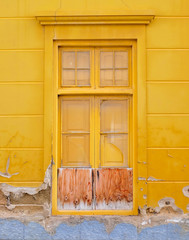 One simple wooden frame painted old window in a yellow wall.