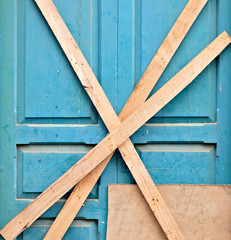 Door to an old house barred and locked with wooden slats nailed down. An old home entrance secured from thieves, squaters and vagrant people.