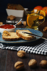 Breakfast, bread and butter with jam and tea on a dark wooden background