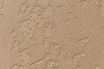 The background is sandy plaster with unfilled mortar islets.