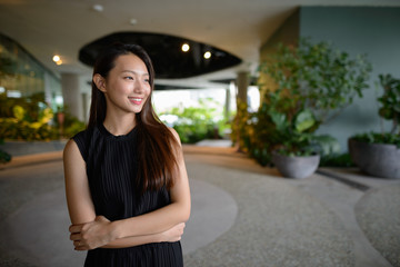 Happy young beautiful Asian businesswoman thinking at the indoor garden