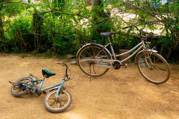 Fototapeta na wymiar Phumĭ O Srâlau Cambodia - Old Bikes on dirt.