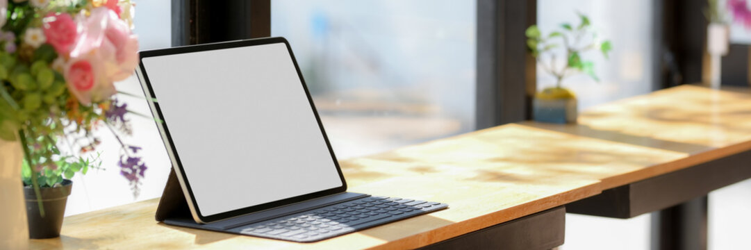 Cropped Shot Of Working Space With Blank Screen Tablet And Decorations On Wooden Counter Bar