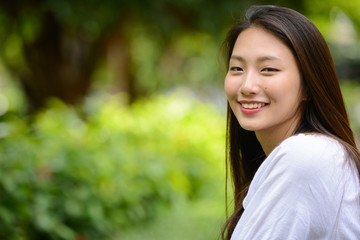 Happy young beautiful Asian teenage girl at the park