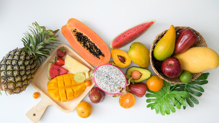 Overhead shot of assortment of exotic fruits and leaves on white background