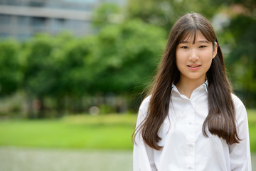 Happy young beautiful Asian teenage girl at the park