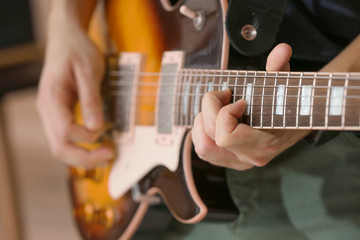 Obraz na płótnie Canvas Young man playing guitar, closeup
