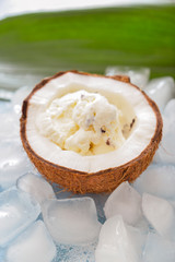 Tasty coconut with ice-cream and ice cubes on color background