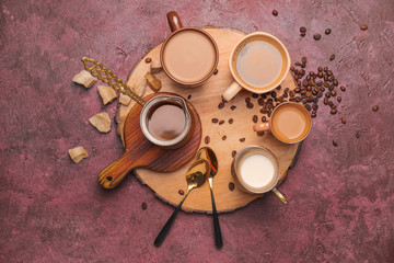 Composition with cups of different coffee on color background