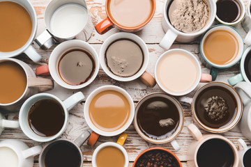 Cups of different coffee on wooden background