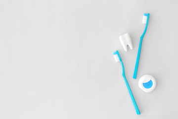 Tooth brushes and floss on light background