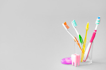 Glass with tooth brushes on light background