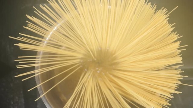 Female chef throwing spaghetti pasta into boiling water. steam rising up. Overhead shot. cook putting down spaghetti in steel pot. Traditional italian pasta. Slow motion. Full hd