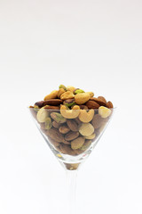 Dry Mixed nuts are in the glass  and Nuts Pile isolated in a white background.selective focus.