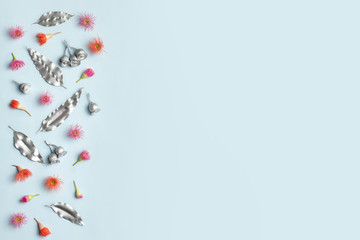 Australian native eucalyptus leaves and gum nuts painted silver plus purple and red flowering gum nuts, frame the composition on a blue background.