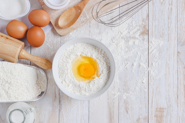 Homemade Dough Recipe (Eggs, flour, milk, sugar) and wooden kneading dough on a wooden table, view from above