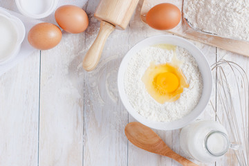 Homemade Dough Recipe (Eggs, flour, milk, sugar) and wooden kneading dough on a wooden table, view from above
