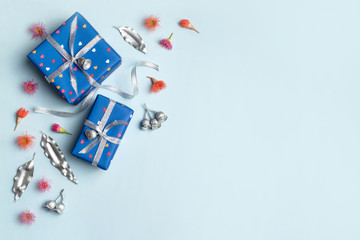 Gifts wrapped in blue hearts paper and tired with silver ribbon. Silver painted eucalyptus leaves and gum nuts, plus flowering gum nuts surround the presents on a blue background..
