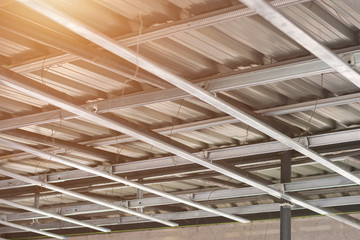 Looking up structure of steel roof frame with iron beams and gray tile roof in construction site.