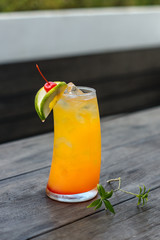 A fresh orange mocktail is served on a wooden table with leaf ornaments.
