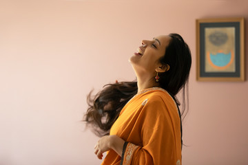 Beautiful woman in saree laughing in her living room. 