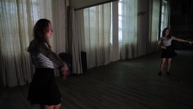Teenage girl dancing in front of a mirror in the dark studio slow motion