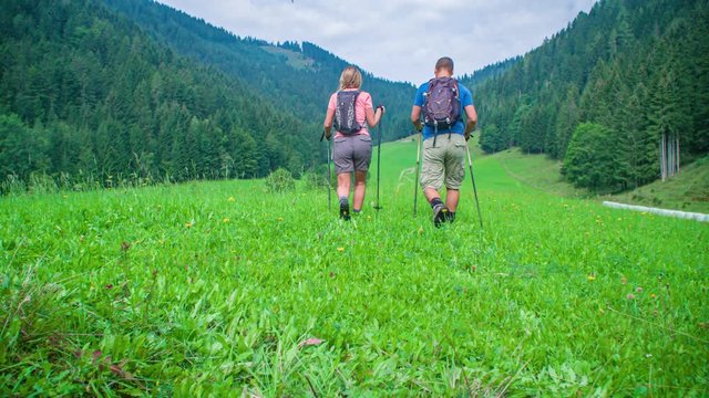 dolly of a man and woman, wearing shorts, hiking, luxuriant view of Topla Valley