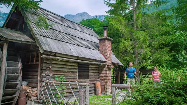 Walking by a wooden mountain cabin with old water mill. Slowmotion hiking adventure. Topla Valley, Slovenia