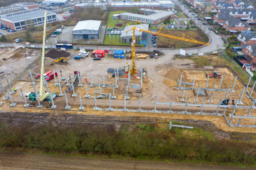 huge concrete pillars are erected on a large construction site using a crane