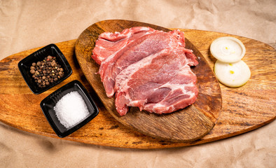 pork on wooden with onion, salt, pepper. top view