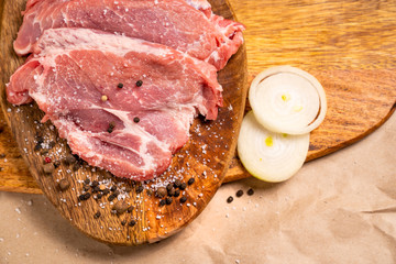 raw pork on wooden Board with salt, pepper, onion