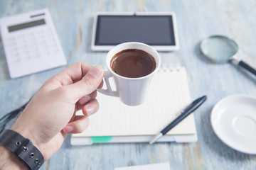 Man holding coffee cup in office desk.