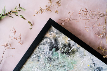 Detail of abstract picture in modern black frame and dried flowers on decorative canvas background. Home decor.