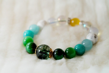 Green and white tone lucky stone bracelet. green moss agate, Green tiger's eye, jade on white wool background. supplement Fortify Fortunate charm and rich