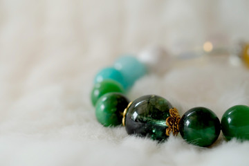 Green and white tone lucky stone bracelet. green moss agate, Green tiger's eye, jade on white wool background. supplement Fortify Fortunate charm and rich
