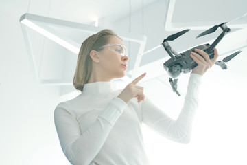 Below view of attractive modern woman operating drone using smart goggles