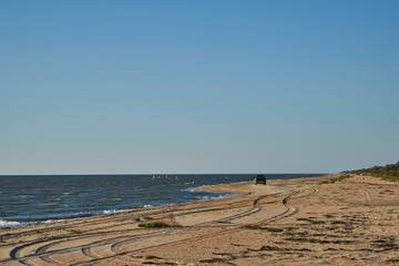 Image of the sea shore. The car is driving along the seashore.