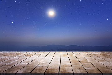 Naklejka na ściany i meble wooden table desk with starry night sky and moon against mountains view in the dark night