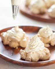 the process of creating Pavlova dessert, decorating the meringue with cream from the culinary bag