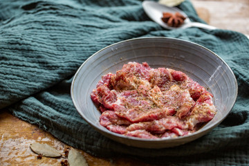Fresh-marinated raw steak with Vanilla and pepper in bowl on wooden background.