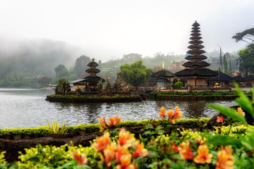 Fototapeta na wymiar Beautiful view of Pura Ulun Danu Bratan with fog and vivid flowers foreground in the morning at Bali, Indonesia.