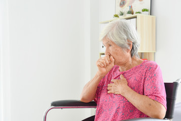 Asian senior woman coughing while sitting on wheelchair