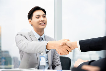 Happy businessman making handshake with businesswoman at meeting room in city office