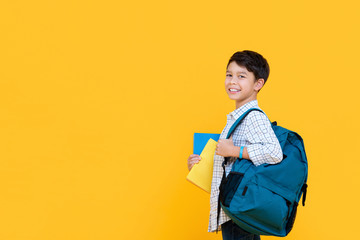 Happy smiling 10 year-old mixed race boy with backpack and books ready to go to school isolated on...