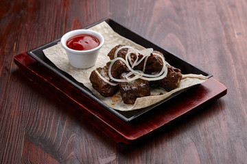 Fototapeta na wymiar Appetizing grilled meat dishes with sauce on a dark wooden table.