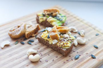 Obraz na płótnie Canvas whole grain toast with avocado and pumpkin and flax seeds, cashews and figs