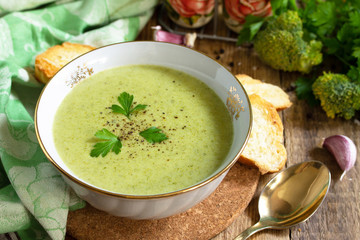 Vegetarian dish. Delicious broccoli cream soup served with garlic croutons on a rustic table.